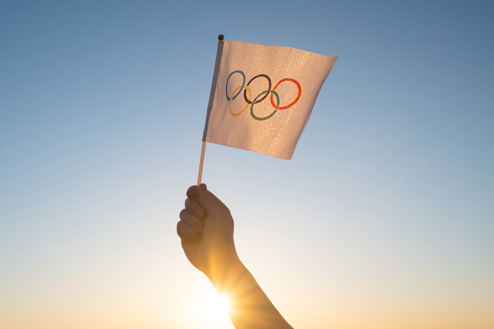 une main tendue tient le drapeau des Jeux Olympiques