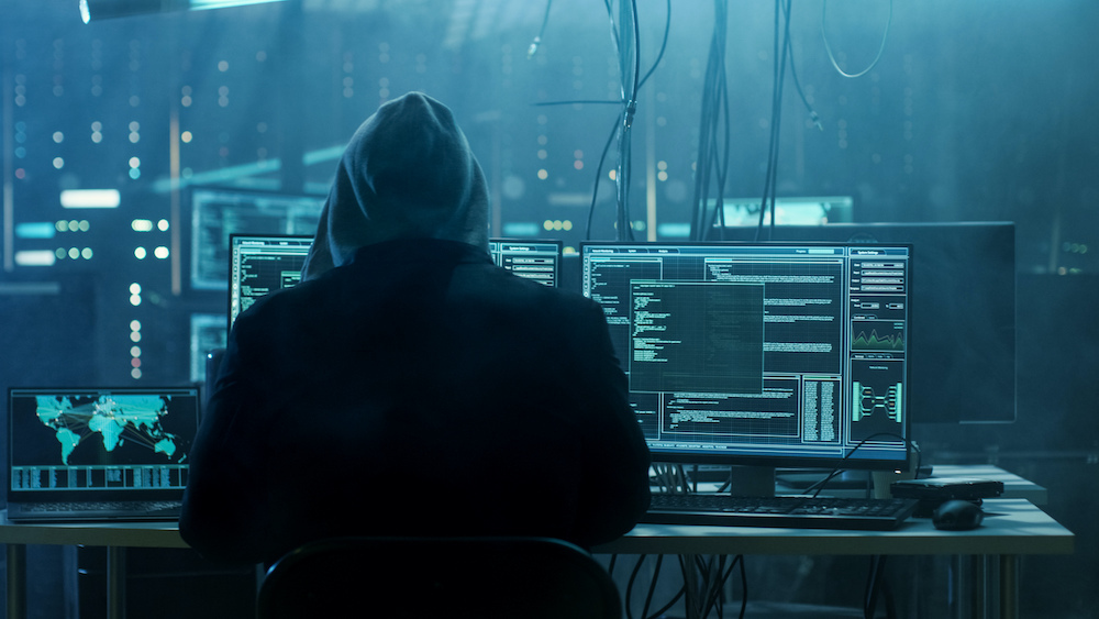 Hacker capuché dans une salle d'ordinateurs.